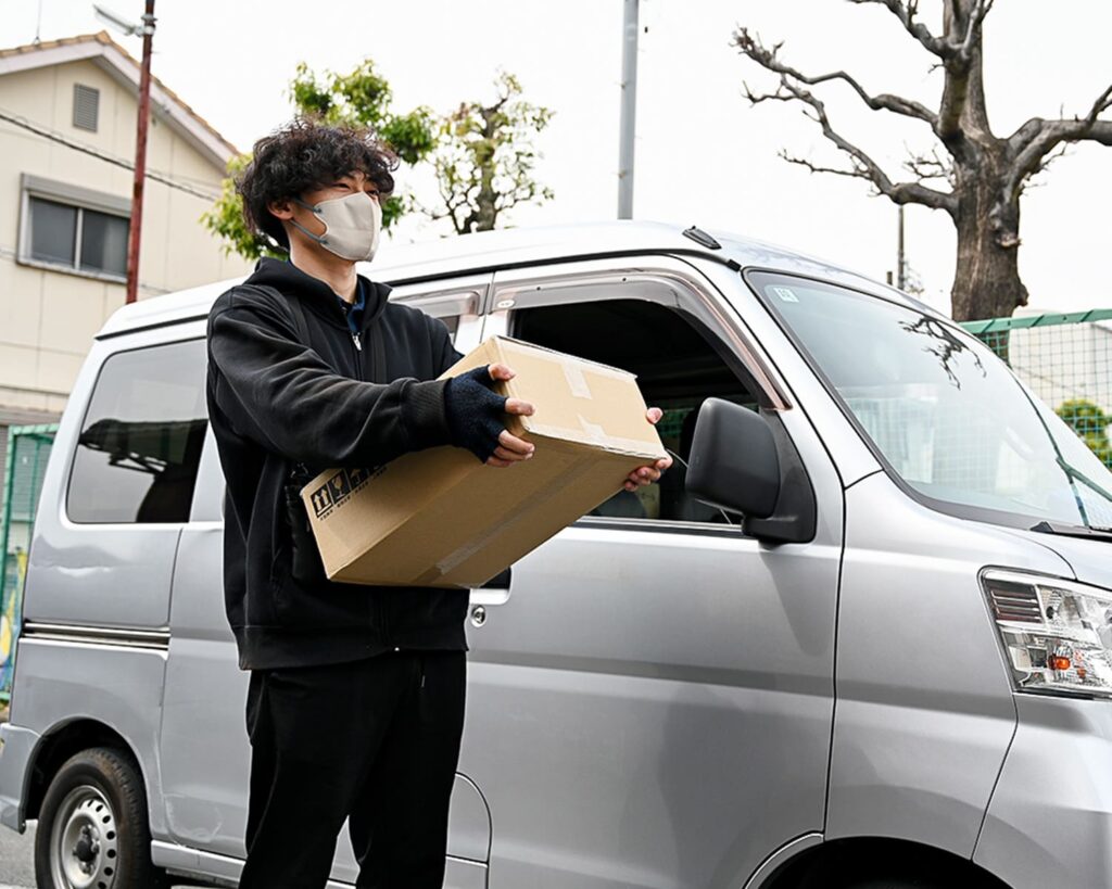 荷物を持つ男性と軽トラ